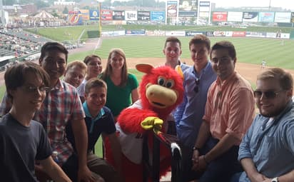 Students and a baseball mascot smile at the camera.