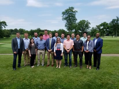 A group of students with High executives smiles for the camera.